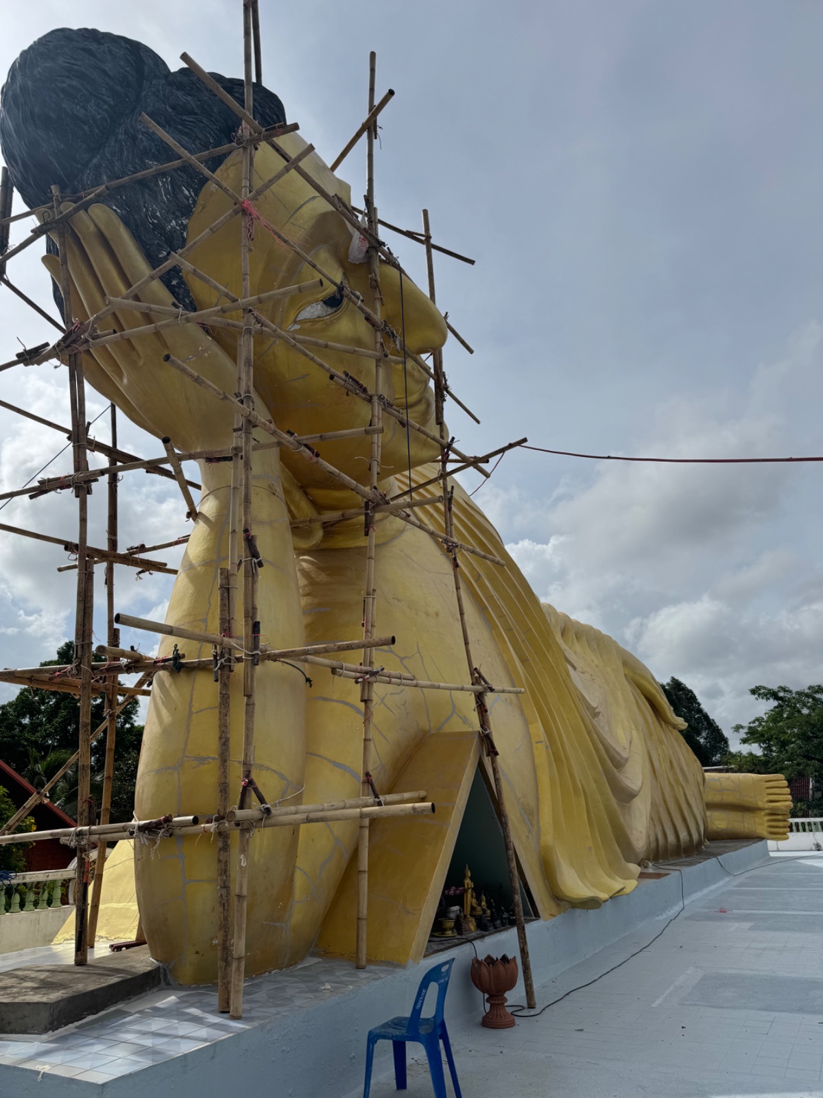 Tête du Bouddha couché du Wat Sri Sunthon entourée d'échafaudages en bambou pendant sa rénovation