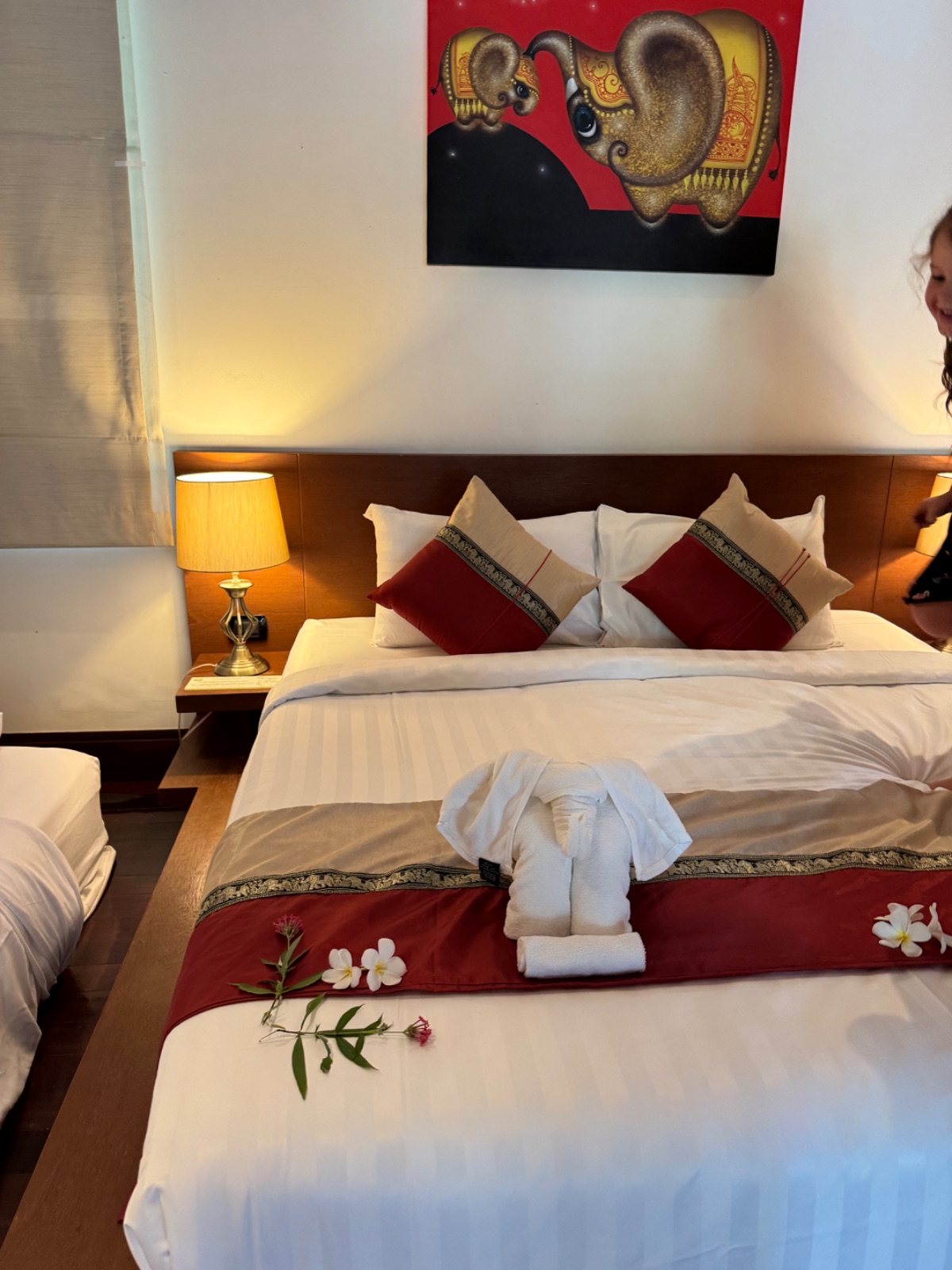 Chambre de la villa avec grand lit, éléphants en serviettes et fleurs de frangipanier disposées sur le couvre-lit