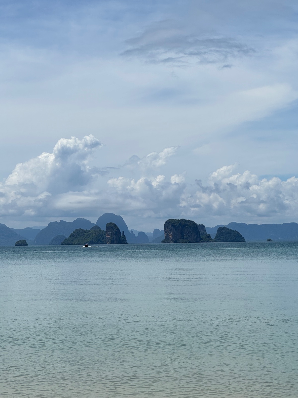 Îlots karstiques de la baie de Phang Nga posés sur une mer calme, vus depuis le bateau