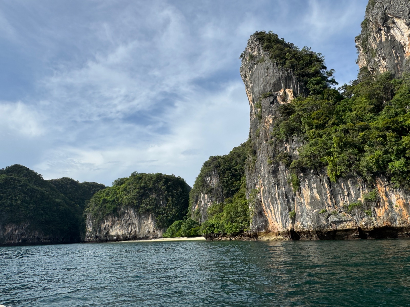 Falaise karstique de la baie de Phang Nga tombant dans l'eau émeraude, vue depuis le long-tail