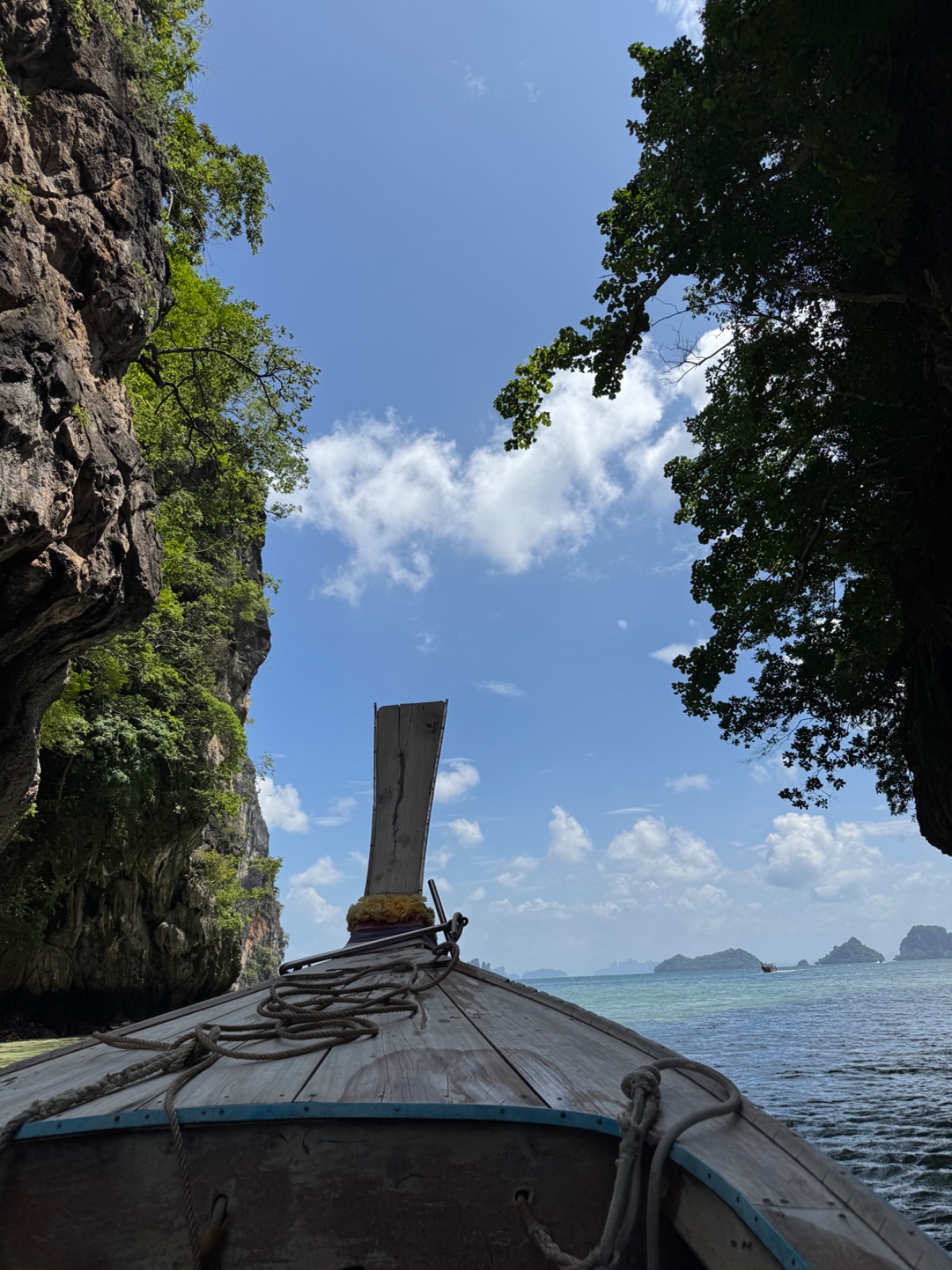 Proue du long-tail passant sous une arche de falaise karstique dans la baie de Phang Nga