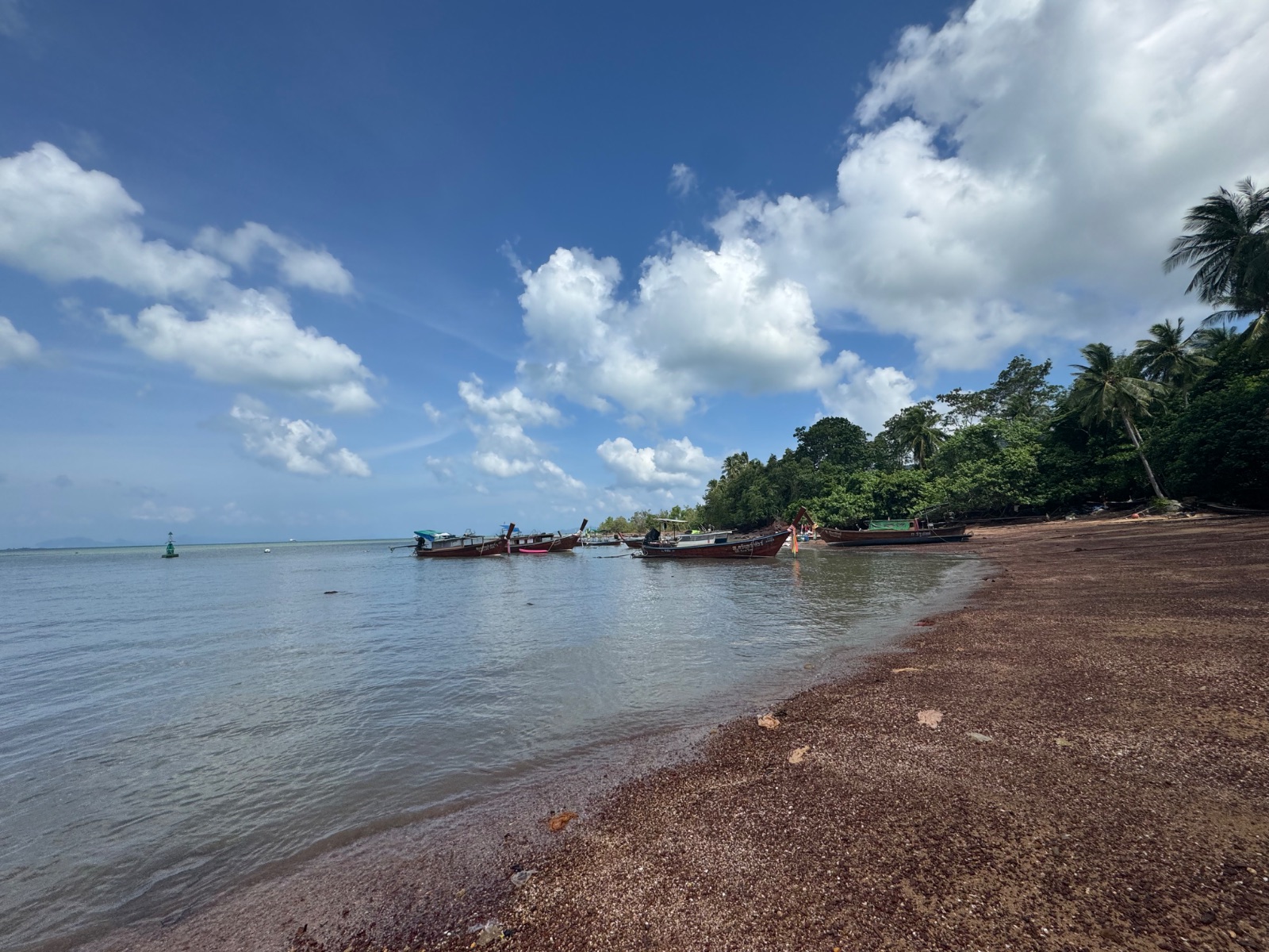 Plage de Koh Lanta couverte de petits cailloux rouges et coquillages, terrain de chasse aux yeux de Shiva