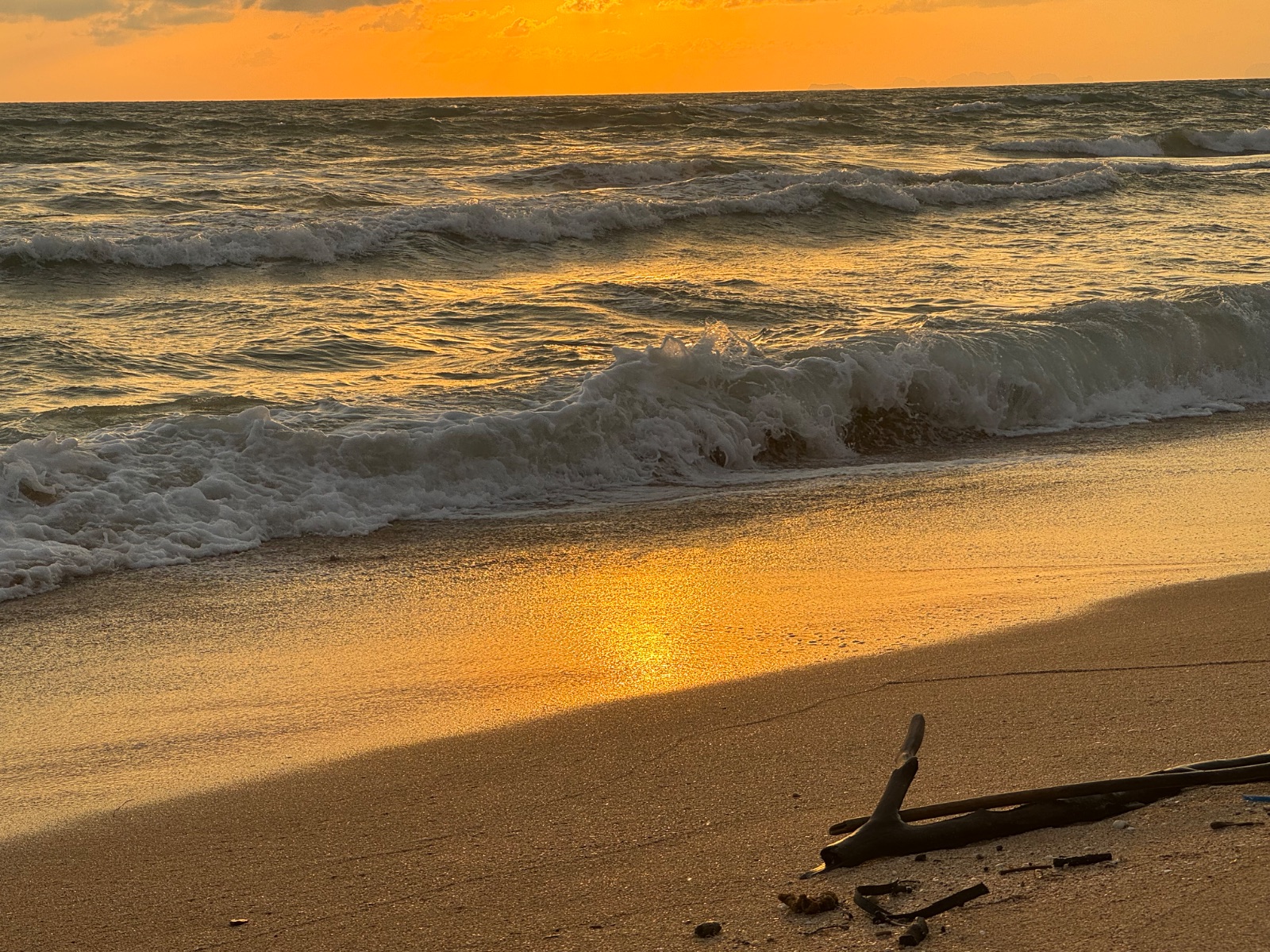 Coucher de soleil doré sur une plage déserte de la côte ouest de Koh Lanta, vagues et sable mouillé