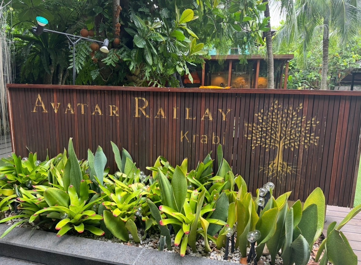 L'enseigne en bois gravé du restaurant Avatar Railay Krabi, entourée de plantes tropicales