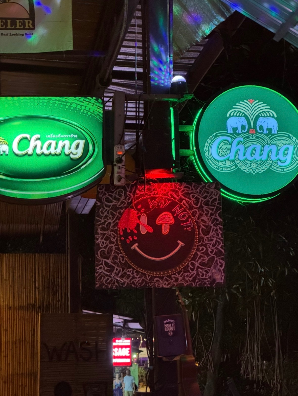 Enseignes lumineuses d'un bar de Railay East la nuit : néons verts de bière Chang et panneau rouge au smiley